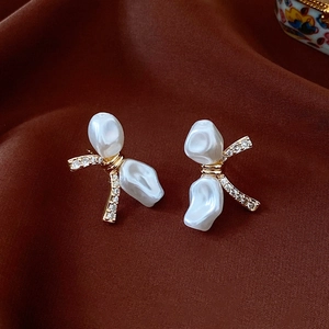 Macro shot of bow earrings with baroque pearls and rhinestones on dark satin