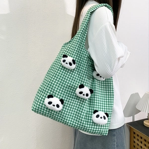 Green checkered canvas tote bag with 3D panda plush charms worn by a model