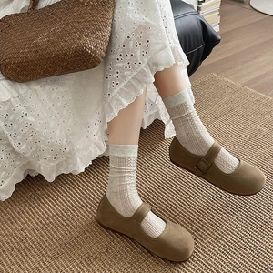 Brown Mary Jane shoes paired with off-white hollowed-out cable knit mid-calf socks