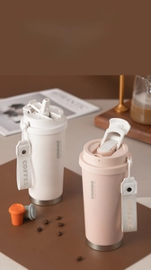 Dual-sip coffee tumblers in cream and pink with woven carry straps and durable steel base