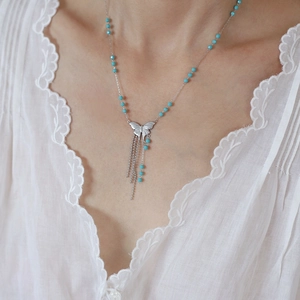 Detail of silver butterfly pendant necklace with turquoise beads and metallic tassels