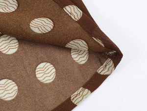 Gros plan sur tissu en mousseline marron à pois blancs avec détails de couture d'ourlet