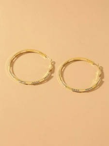 Detailed close-up of golden oversized hoop earrings with sparkling crystal accents