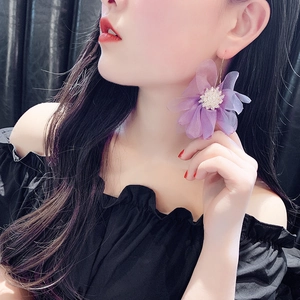 Dettaglio di un orecchino a fiore in tulle viola con perle indossato da una modella