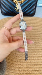 Nahaufnahme des silbernen Zifferblatts mit eleganter zweireihiger Perlenarmband