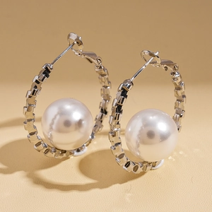 Macro view of geometric silver earrings with large white pearls on a soft background