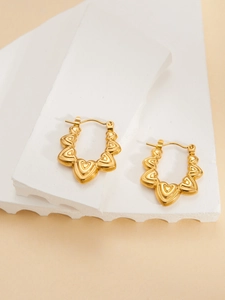 Detailed view of gold stacked heart earrings on white stone display platform