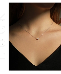 Macro shot of silver heart pendant necklace with shimmering crystals on model neck