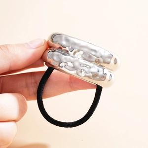 Close-up of black elastic hair tie with irregular silver metal wave accessory