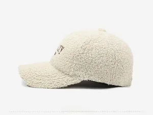 Detailed side view of cream teddy fleece baseball cap with brown letter embroidery