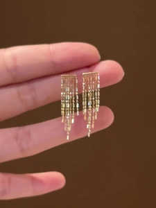 Gros plan de boucles d'oreilles pendantes à franges dorées avec fines perles métal
