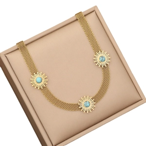 Golden sun-shaped turquoise pendant necklace set with woven chain in a beige box
