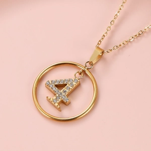 Detail of gold necklace with a crystal-encrusted number 4 pendant on pink background