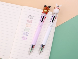 Detail view of Christmas multi-color pens with cartoon elk and snowman toppers on a notebook