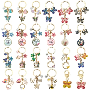 Golden metal keychains with floral, bee and Mother's Day enamel charms on white background