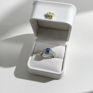 Detail of a blue heart zircon ring with silver setting in a white jewelry box