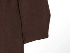 Detailed macro view of dark brown knitted fabric texture and premium stitching finish