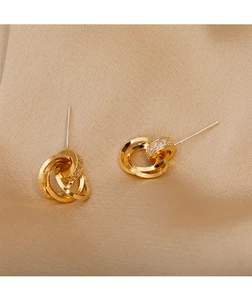 Close-up of gold interlocking triple hoop earrings with cubic zirconia on satin