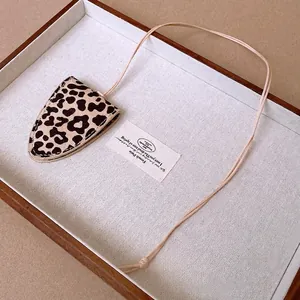 Faux leather leopard print glasses bag necklace with a pink string in a wooden tray
