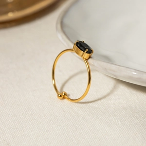 Detail of 18k gold plated stainless steel ring with an oval black zircon on ceramic