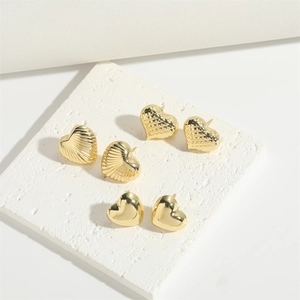 Detailed view of three pairs of golden heart stud earrings with diverse metal textures