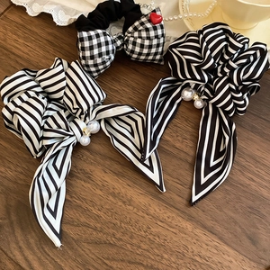Detail of striped and plaid scrunchies with white pearls and red heart charm