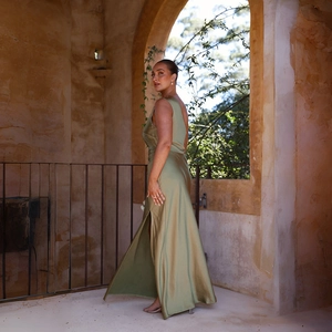 Close-up of olive green satin dress fabric featuring high slit and draped texture