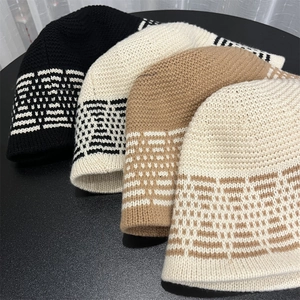 Close-up of geometric jacquard knit bucket hats in black, beige and camel wool colors
