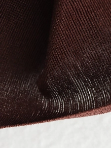 Macro shot of dark brown fine ribbed knit fabric showing soft texture and glossy finish