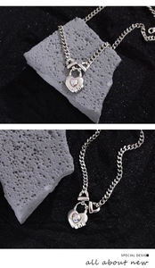Detailed shot of silver heart lock necklace with iridescent gemstone on Cuban chain link