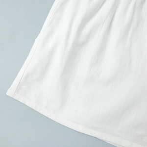 Detailed macro view of white cotton fabric texture with refined ruffles and hem stitching