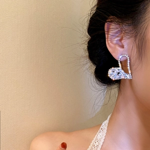 Close-up of model wearing silver hollow heart earrings with sparkling cubic zirconia stones