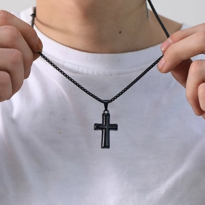 Punk style polished black stainless steel cross pendant necklace worn on a white t-shirt