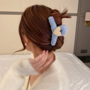 Detail of blue plush hair claw clip with cream heart accent on model's hair