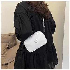 Detail of white nylon crossbody bag featuring butterfly ornament and patterned wide strap