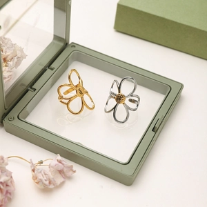 Détails de bagues fleurs bicolores or et argent présentées dans un écrin cadeau de luxe