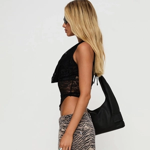 Détail d'un haut licou sexy en dentelle noire avec pantalon zèbre et sac en cuir