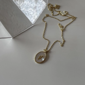 Detailed close-up of golden tulip relief pendant on a white mother-of-pearl base