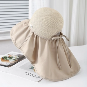 Dettaglio del cappello da sole a tesa larga con trama in paglia e fiocco decorativo sul retro
