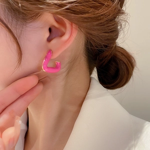 Detail of vibrant hot pink enamel earrings with golden geometric metal base design