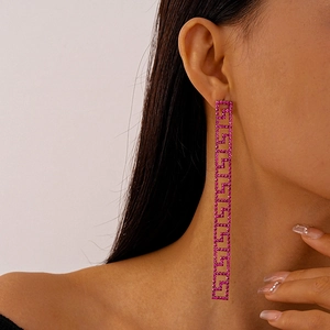 Close-up of pink Greek Key earrings with sparkling rhinestones worn by a model