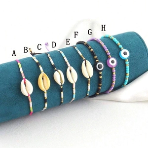 Detailed view of colorful evil eye and shell braided bracelets on blue velvet display