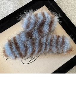 Macro detail of striped plush shark hair clip with soft brown and blue faux fur texture