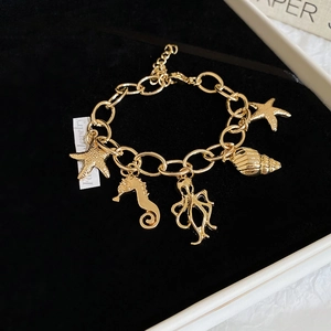Detail of gold ocean-themed charm bracelet with starfish and seahorse on black velvet