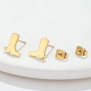 Minimalist gold cowboy boot earrings for women on a white stone pedestal display