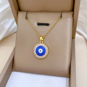 Macro detail of gold evil eye pendant with blue enamel and sparkling white zircon pavé