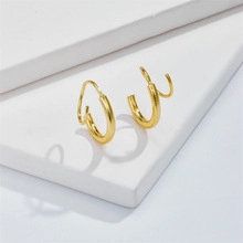 Polished 14K gold plated double spiral C-shaped earrings on white geometric display stand