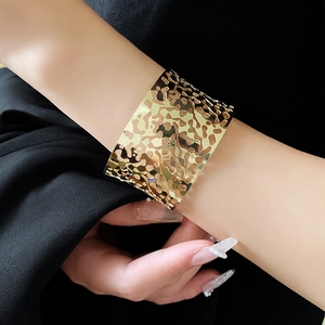 Detailed view of wide gold irregular cutout cuff bracelet with polished lava texture