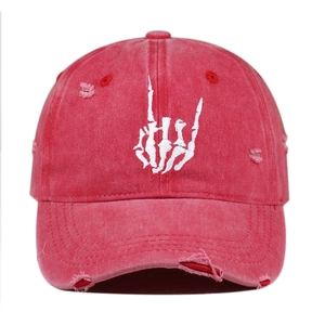 Detailed close-up of white skull gesture embroidery on red washed distressed baseball cap