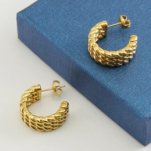Macro view of C-shaped twisted rope earrings with 18k gold vintage woven texture